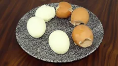 Gekookte en gepelde eieren op een bord met eierdoppen, op een houten tafel
