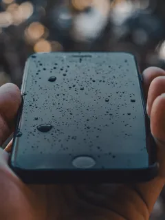 Zwarte iPhone met waterdruppels erop, close-up detail