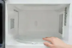 Schone magnetron met open deur en een hand die het draaiplateau aanraakt